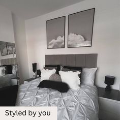 a bed with white sheets and pillows in front of two framed pictures on the wall