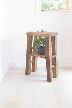 a small wooden table with a potted plant sitting on it's legs in front of a window