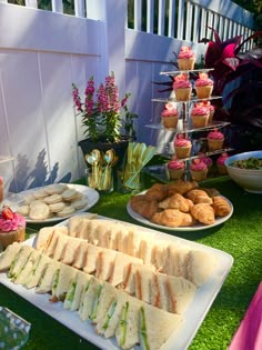 an assortment of sandwiches and cupcakes are on display at a garden themed party