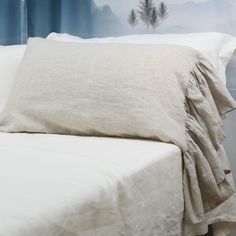 a bed with white sheets and pillows in front of a mountain scene painted on the wall