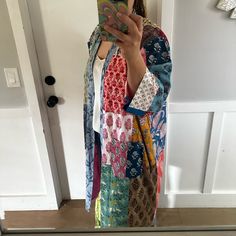 a woman taking a selfie in front of a door wearing a colorful kimono