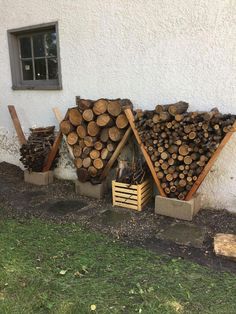 several stacks of logs sitting next to each other on the side of a white building