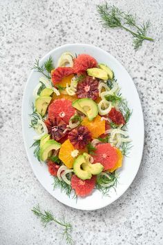 a white plate topped with cut up fruit and veggies on top of a table