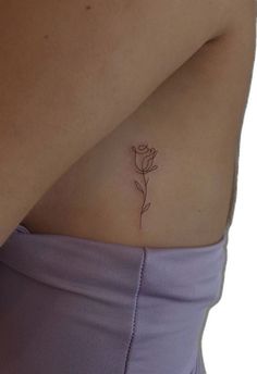 a woman's stomach with a single flower tattoo on her left side ribcage