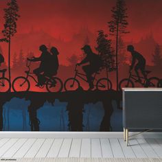 the silhouettes of people riding bikes against a red and blue background wall mural in a living room