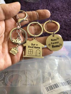 a person holding several different key chains in their hand with the words home and first home engraved on them