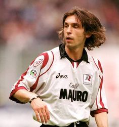 a man with long hair wearing a white and red soccer jersey running on the field