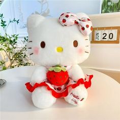 a hello kitty stuffed animal sitting on top of a table with a strawberry in its hand