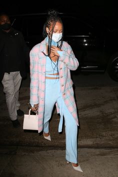 a woman wearing a face mask while walking down the street with her hand on her hip