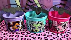 three buckets with cartoon characters painted on them sitting on a pink tablecloth and leopard print