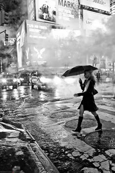 a woman walking across a street holding an umbrella