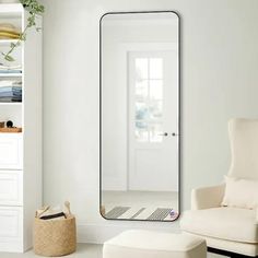 a living room with white furniture and a large mirror on the wall next to a chair