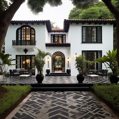 a large white house surrounded by trees and plants in front of the entrance to it