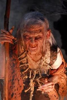 an old woman dressed in costume holding a stick