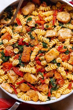 pasta with chicken, spinach and tomatoes in a skillet ready to be eaten