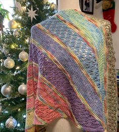 a knitted blanket sitting on top of a table next to a christmas tree