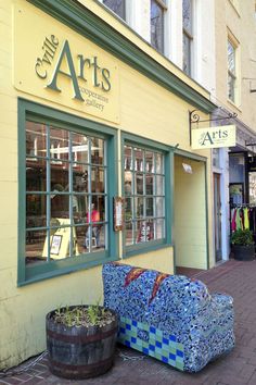 a blue couch sitting in front of a store on the side of a street next to potted plants