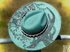 FLORAL ANTLER FEDORA Wide brim. Sea-foam green color custom hand burn fedora. Handmade. Adjustable inside ribbon. Comes as pictured. Item Details: Branded Wide Brim HatsEach hat is hand burned for a custom branded design, because of that each order will vary slightly. Hat band is included in the order. Please feel free to message me with any customization requests. These are quite literally completely customizable. Due to the custom nature of our hats, all purchases are nonreturnable and nonrefu Green Western Fedora For Summer, Green Flat Brim Hat For Country Events, Green Summer Western Fedora, Green Short Brim Hat For Country Events, Green Hat Bands For Kentucky Derby, Adjustable Green Fedora For Country Events, Green Fedora For Country Events, Artisan Adjustable Green Hat Bands, Green Summer Felt Hat With Curved Brim