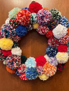 a multicolored wreath with pom - poms hanging from it