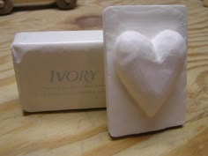 a white heart in a box on a wooden table next to a soap bar that says ivory