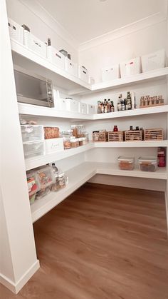 an organized pantry with white shelving and wood flooring is pictured in this image