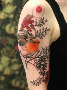 a woman's arm with a bird and berries tattoo on her left upper arm