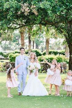 a bride and groom walking with their flower girls down the aisle in front of them