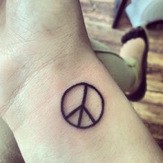 a small peace sign tattoo on the wrist