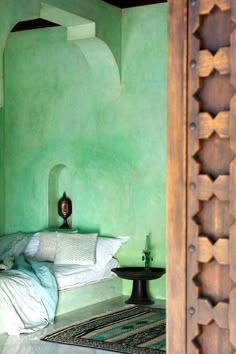 a bed in a room with green walls and white pillows on it's headboard