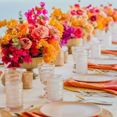 the table is set with flowers in vases and plates