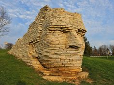 a large brick face on top of a green field