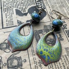 * These beauties feature a stunning enameled component by artist Linda Younkman. I added the poly clay Humblebead to highlight the lovely blues and greens. Pretty!  * earrings measure 3 inches in full and are a bit heavier than most earrings * Designed in Poestenkill NY * NOTE: Wearing in water or to the gym is not recommended  * NOTE:  As with most jewelry , do not force an adjustment if a section becomes mis-aligned. Just give a gentle tug or wiggle and it will straighten out easily. * DISCLAIMER: other items used in photo are not for sale, nor are they included in any purchase. Green Enamel Earrings With Artistic Design, Unique Hand Painted Metal Earrings, Artisan Green Earrings With Artistic Design, Unique Hand Painted Turquoise Earrings, Unique Enamel Dangle Jewelry, Handmade Turquoise Enamel Earrings, Artisan Enamel Jewelry With Ear Wire, Green Artisan Enamel Earrings, Handmade Artistic Green Earrings