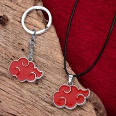 two red clouds are hanging from a silver chain on a wooden surface with a red shirt in the background