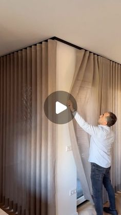 a man standing on top of a bed next to a window covered in drapes