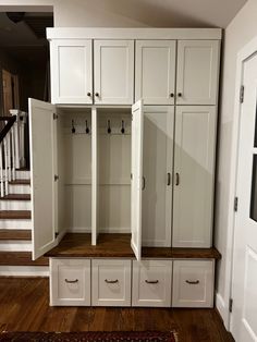 an entryway with white cabinets and drawers on the floor next to a stair case