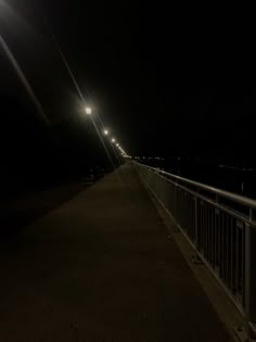 a person standing on a bridge at night with their cell phone up to their ear