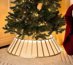 a small christmas tree in a room with a lamp on the floor next to it