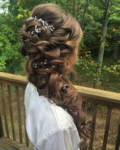 a woman with long hair and flowers in her hair is sitting on a wooden bench