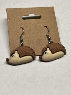 a pair of hedgehog earrings are shown in front of a cardboard package on a table