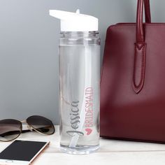 a clear water bottle next to a red handbag and sunglasses