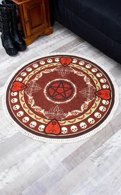 a round rug with skulls and pentagrams on the floor next to a black couch