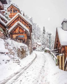 a snow covered street with wooden buildings and steps leading up to the top of it