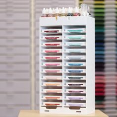 a white display case filled with lots of different types of pens and pencils on top of a wooden table