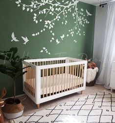 a baby's room with a white crib and green wall painted with birds