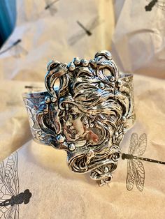 Art Nouveau style cuff.  Magnificent hand crafted Alphonza Mucha style Lady Cuff. From MyElegantThings Design Studio"  Antique silver plated over brass cuff. Engraved cuff with gorgeous flowers and vines and leaves. Vintage style very limited edition Cuff is an engraved and gorgeous garden piece. 1 inch width. Woman piece is 1-1/2 inches. Gorgeous and what a statement. Vintage Antique Silver Cuff Bracelet, Artistic Silver Bangle Bracelet, Artistic Silver Bangle Bracelets, Silver Collectible Cuff Bracelet, Artistic Silver Bangle, Handmade Antique Silver Cuff Bracelet For Wedding, Artistic Silver Bangle Jewelry, Ornate Silver Adjustable Cuff Bracelet, Ornate Adjustable Silver Cuff Bracelet