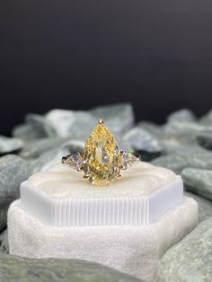 a yellow diamond ring sitting on top of a rock