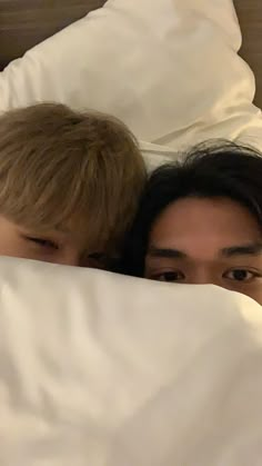 two people laying in bed under the covers