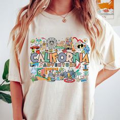 a woman wearing a white t - shirt with the word california written in colorful letters