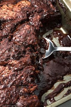 a fork is stuck into some meat in a pan with chocolate sauce on the side