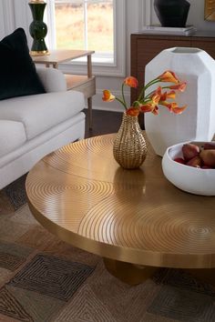 a living room with a couch, table and vase filled with flowers on top of it